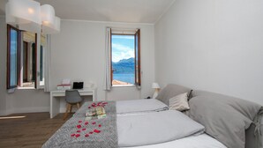 A bedroom with a bed, a desk, and a view of mountains. - Casa Maria Menaggio (Menaggio)