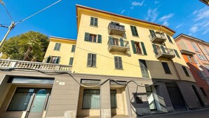 A multi-story building with balconies, a garage, and a clear sky. - Casa Maria Menaggio (Menaggio)