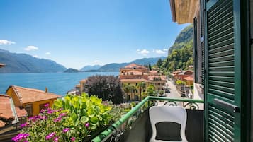 A balcony with a view of a lake, buildings, and mountains.