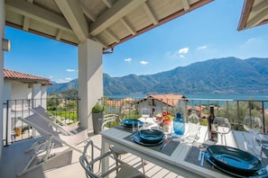 A balcony with a table set for dining, overlooking a mountainous landscape and a body of water. - Sant' Agata Bellavista (Tremezzina)