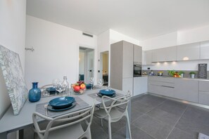A modern kitchen with grey cabinets, a dining area with a table set for two, and a large window.