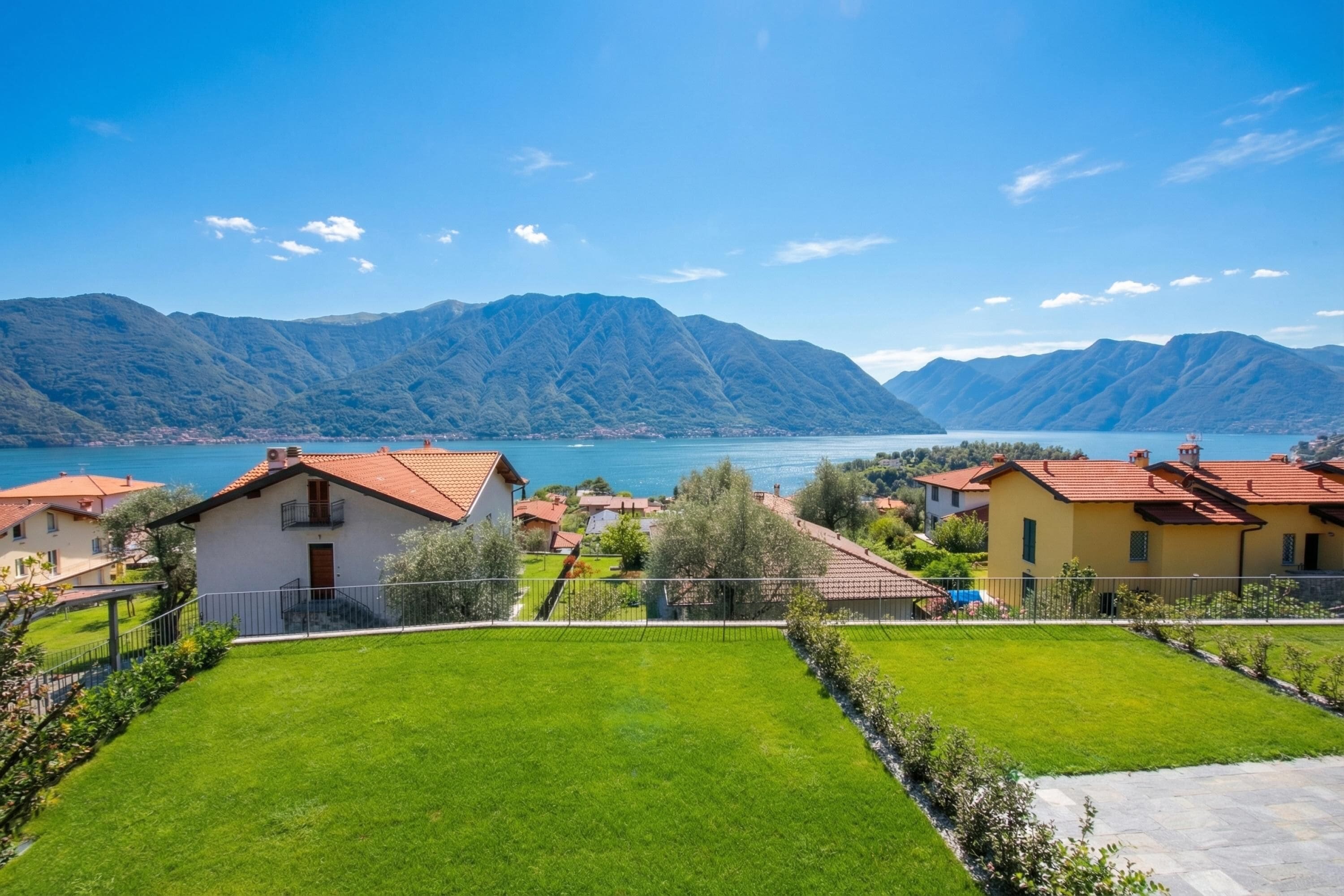 Un quartiere residenziale con case, un prato curato e montagne sullo sfondo.