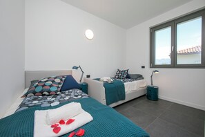A modern bedroom with two beds, teal bedding, and bedside lamps. - Sant' Agata Bellavista (Tremezzina)