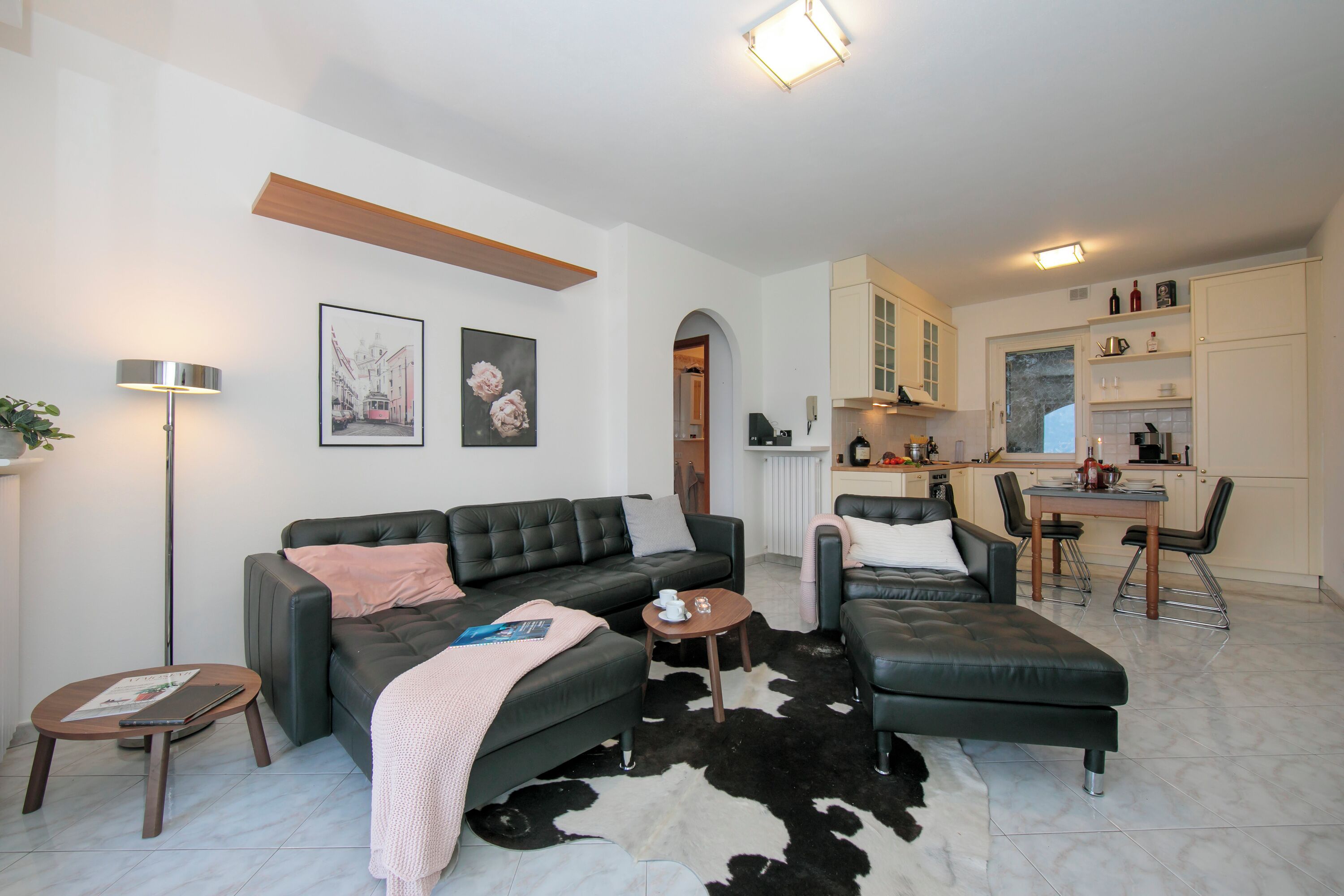 A modern living room with a sofa, a coffee table, and a dining area with chairs and a table.