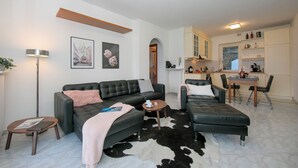 A modern living room with a sofa, a coffee table, and a dining area with chairs and a table. - Sonenga Panoramic Terrace (Menaggio)