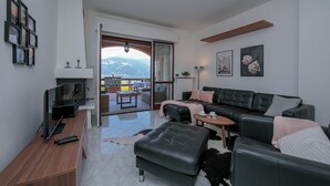 A modern living room with a sofa, ottoman, and a flat-screen TV on a wooden table. - Sonenga Panoramic Terrace (Menaggio)