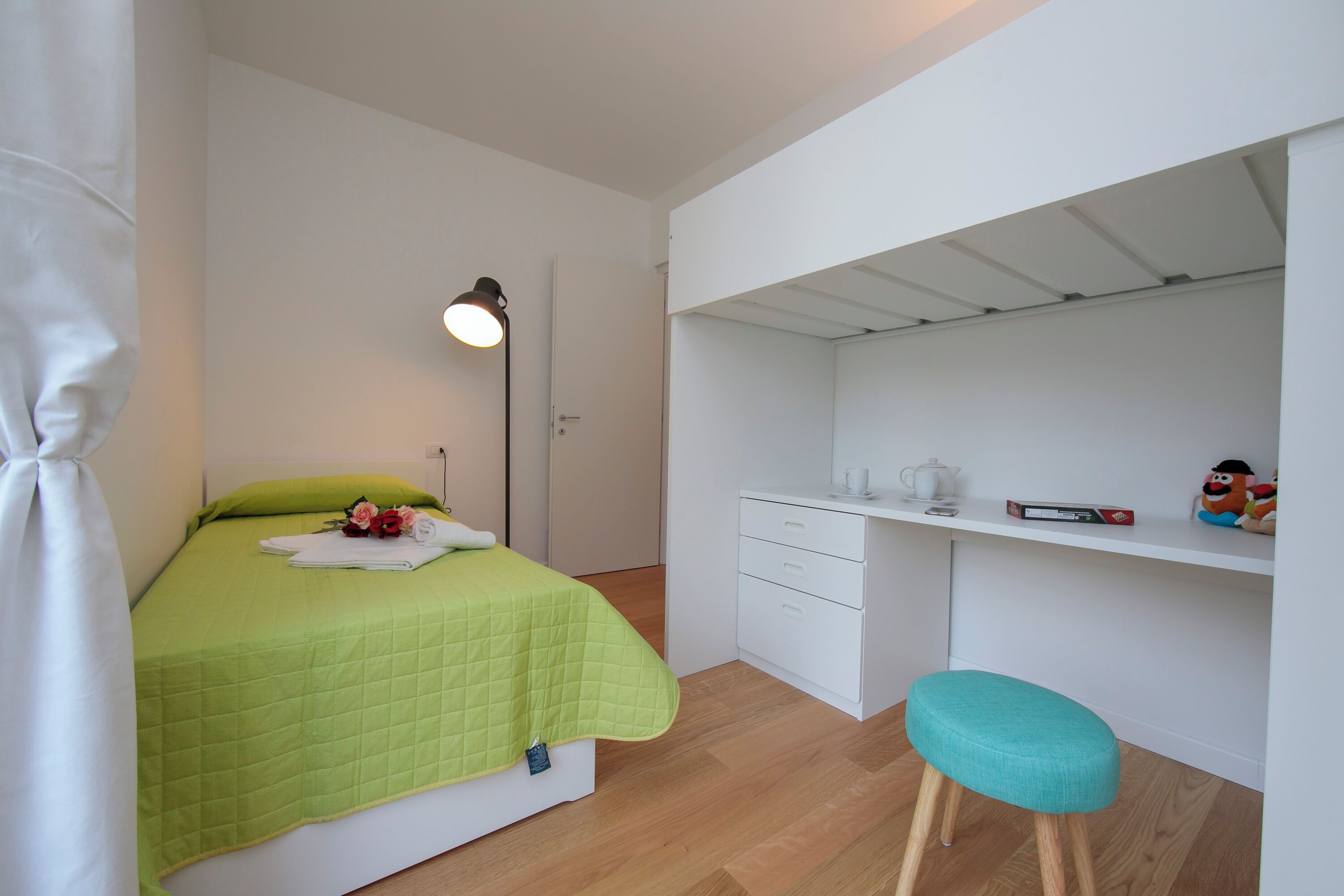Une chambre à coucher avec un lit, un bureau, une chaise et une table de chevet.