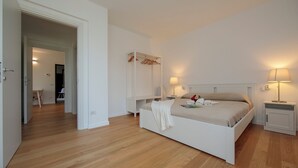 A bedroom with a bed, bedside tables, a wardrobe, and a door leading to another room. - Argegno Home (Argegno)