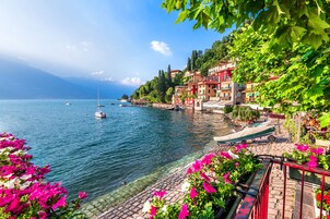 Un hotel frente al lago, con vistas despejadas al agua, un camino de piedra y edificios de colores.