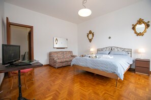 A bedroom with a bed, bedside tables, a desk with a computer, a chair, a mirror, and a wall-mounted picture. - La Casa del Vitt (Menaggio)