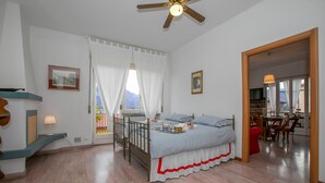 A bedroom with a bed, a desk, a chair, a ceiling fan, and a window with curtains. - La Casa del Vitt (Menaggio)
