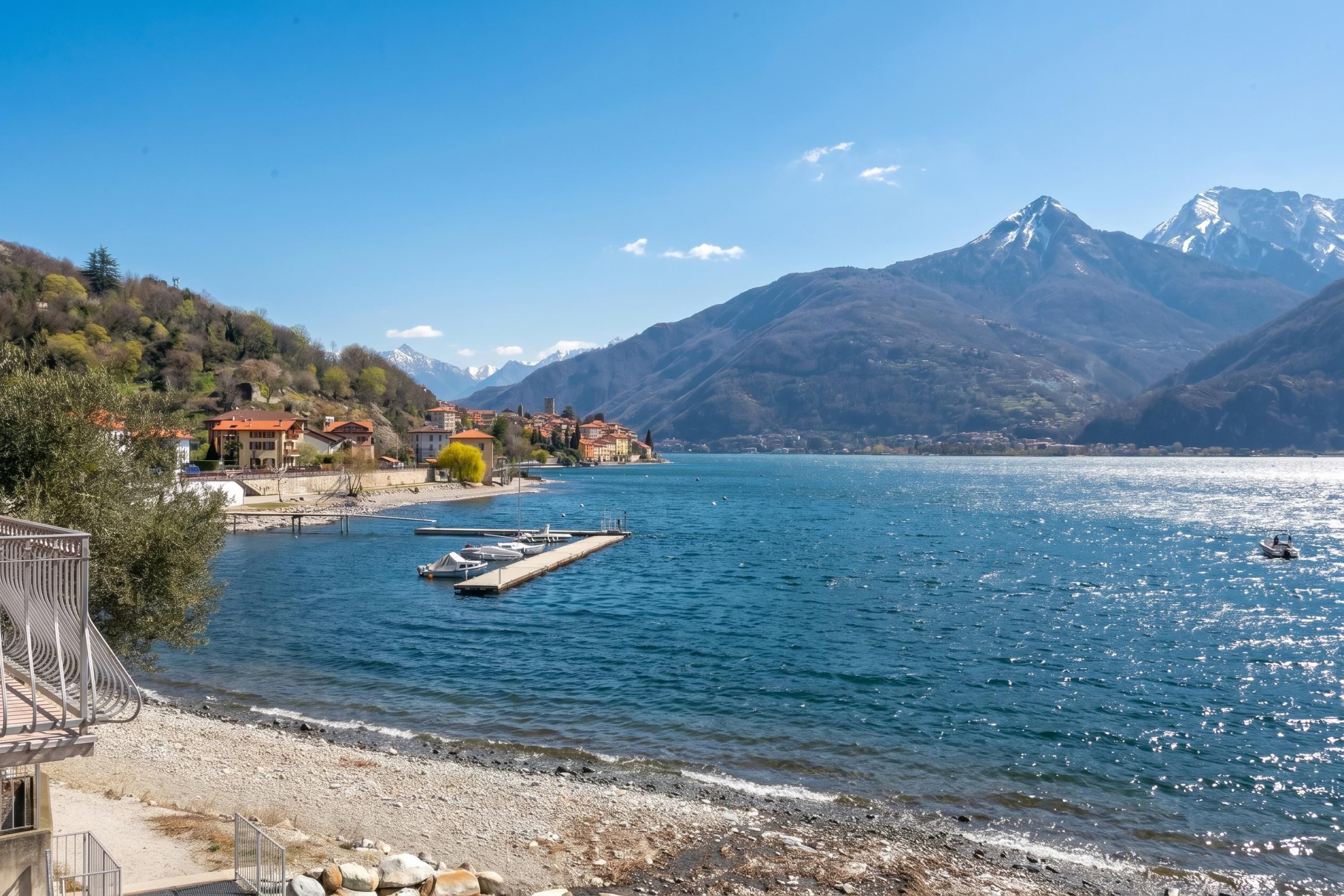 A lakeside view with a dock, boats, and a mountainous backdrop.