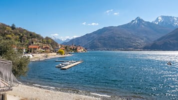 A lakeside view with a dock, boats, and a mountainous backdrop.