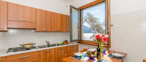 A kitchen with wooden cabinets, a dining table set for two, and a window with a view of trees and mountains.