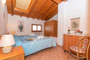 Un dormitorio con cama, escritorio, silla, armario, ventana y un cactus pintado en la pared.