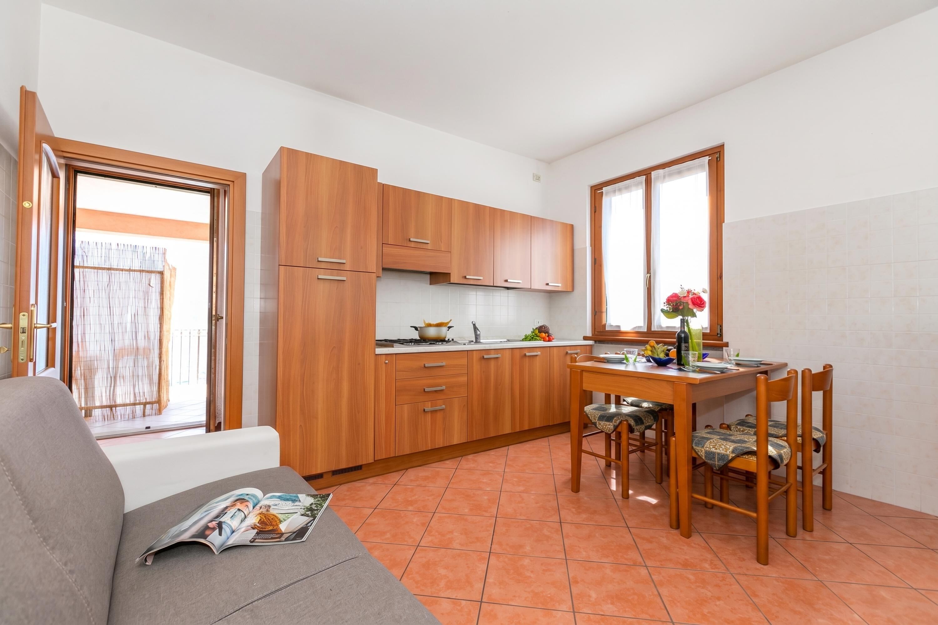 Eine kleine Küche mit Holzausstattung, einem Esstisch mit Stühlen und einer Couch.