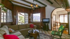 Una sala de estar acogedora con sofá, sillón mecedora, mesa de centro y televisor.