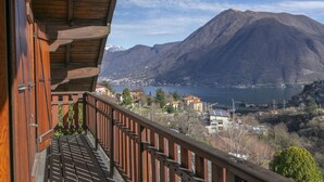 Un balcón de madera con vistas a una montaña y un lago.