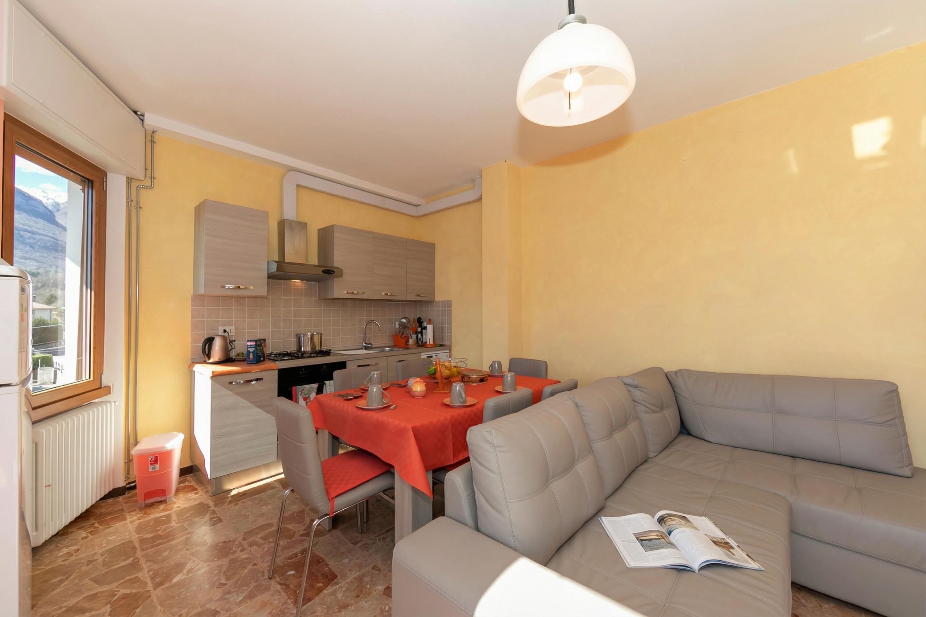 A modern kitchen with a dining area, a sofa, and a window.