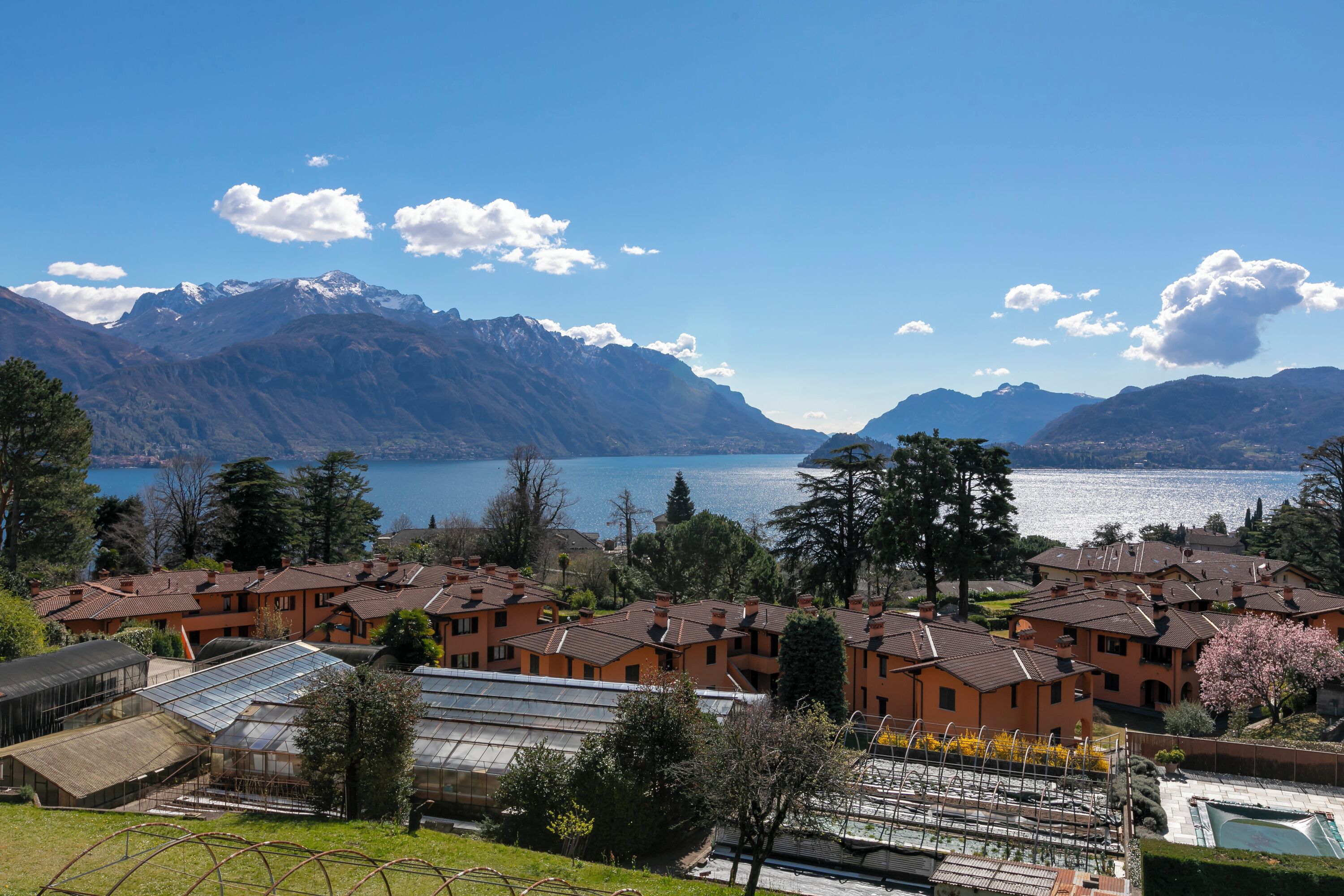 Un quartier résidentiel avec des maisons, une piscine et une vue sur un lac et des montagnes.