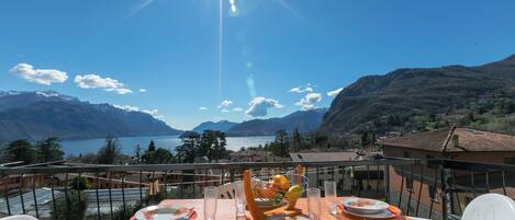 A table set for two with a mountain view, a clear sky, and a body of water in the background.