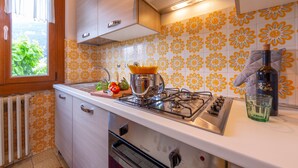 Una cucina con piano cottura a gas, forno integrato e una finestra vista verde.