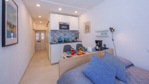 Een kleine kamer met een bed, een kitchenette en een eethoekje.
