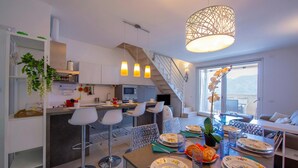 A modern kitchen with a central island, bar stools, and a dining area with a table set for two.