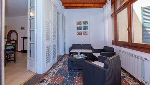A room with a tiled floor, a sofa, a small table with a tray, and a window with shutters. - Casa Mira Al Lago (Menaggio)