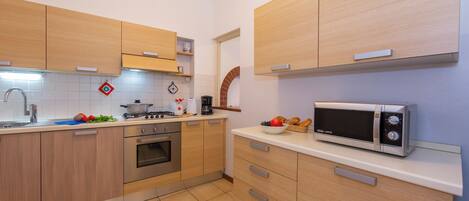A modern kitchen with wooden cabinets, a microwave, a stove, and a sink.