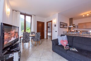A modern living room with a TV, sofa, and dining area. - Bellano Terrazzo (Bellano)