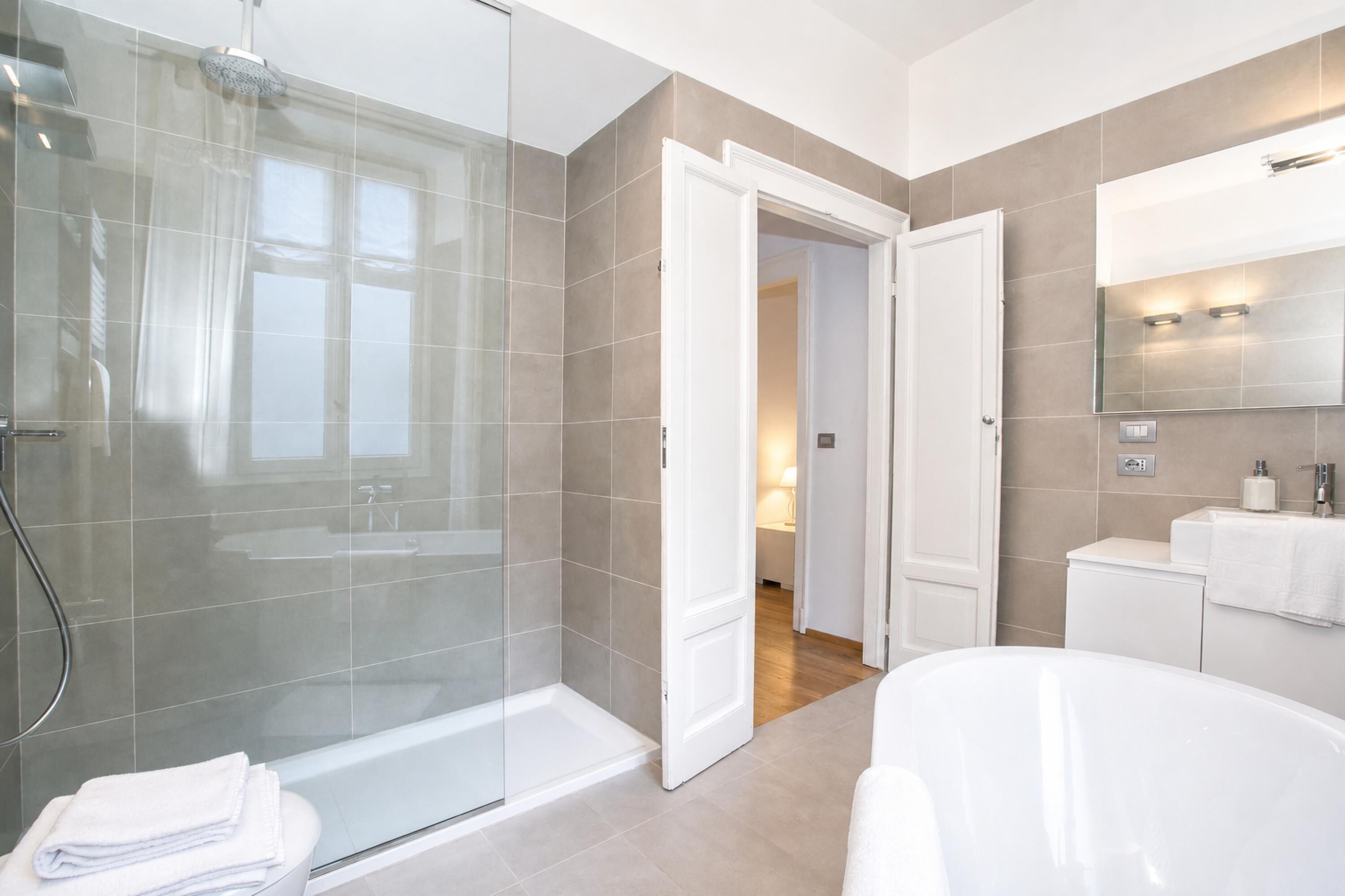 Une salle de bain moderne avec une douche à parois de verre, une baignoire sur pieds et un meuble-lavabo avec un miroir.