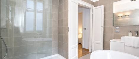 Une salle de bain moderne avec une douche à parois de verre, une baignoire sur pieds et un meuble-lavabo avec un miroir.