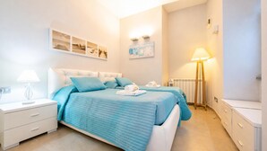 A bedroom with two beds, a bedside table with a lamp, a wall-mounted artwork, and a radiator. - Villa Lucia Laglio (Laglio)