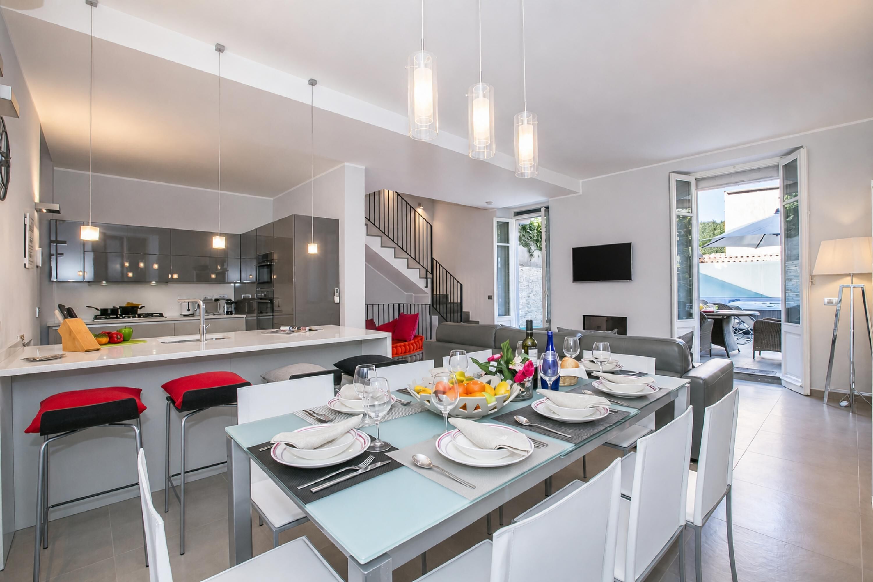 A modern kitchen with a central island, bar stools, and a dining area set for six.