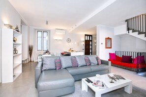 En moderne stue med en grå sofa, en rød sofa, et hvidt sofabord og en trappe.