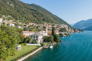 A lakeside town with buildings along the shore, a prominent tower, and a gazebo. - Villa Lucia Laglio (Laglio)