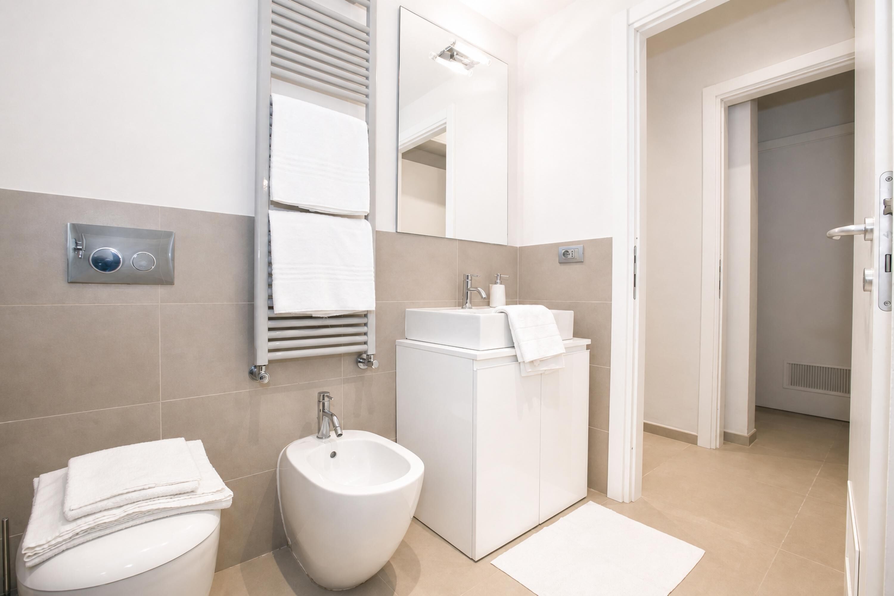 A modern bathroom with a bidet, sink, and mirror.