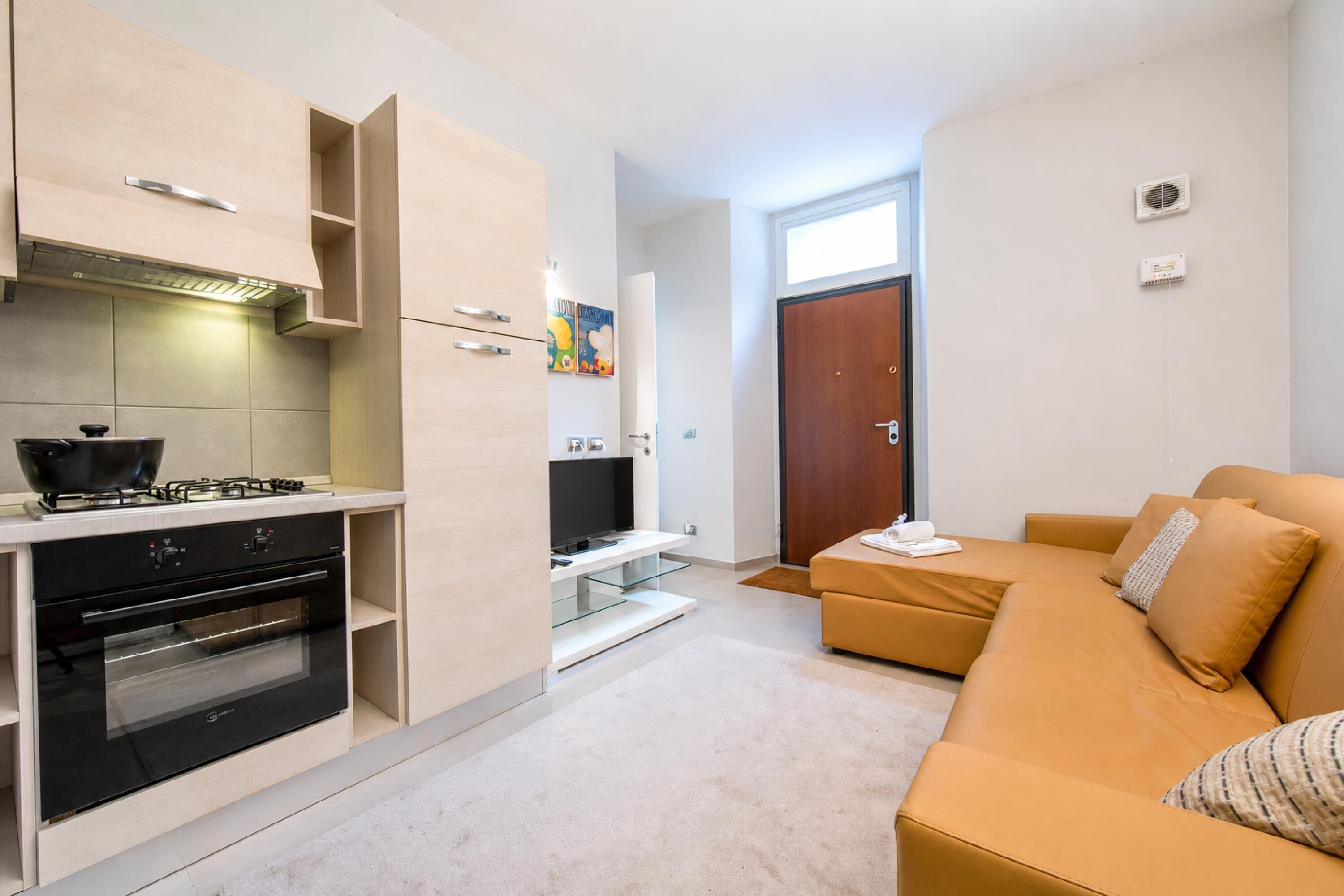Una cucina moderna con elettrodomestici integrati, una vetrina e un divano nella zona giorno.
