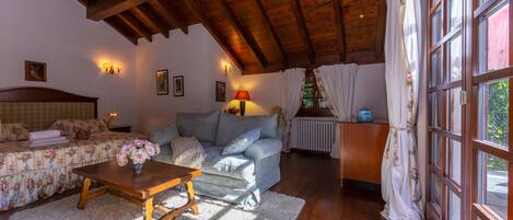 A cozy living room with a wooden ceiling, a sofa set, a coffee table, and a window with curtains.