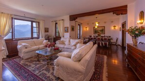 Amplia sala de estar con un gran ventanal, un comedor y techo de madera.
