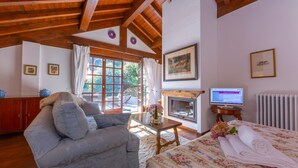 Una habitación acogedora con sofá, cama con ropa de cama estampada, chimenea y televisor.