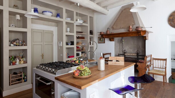 A kitchen with a central island, wooden bar stools, and a rustic ceiling. - Villa Silvana (Oliveto Lario)