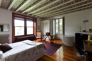 A bedroom with a bed, a dresser, a television, and a window.