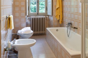 A bathroom with a toilet, sink, bathtub, and window.
