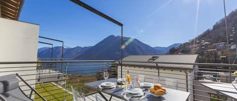 An outdoor dining area with a table set for two, overlooking a mountainous landscape.