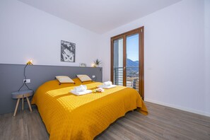 Un dormitorio con una cama grande, una mesita de noche, una ventana con vistas y un cuadro colgado en la pared.