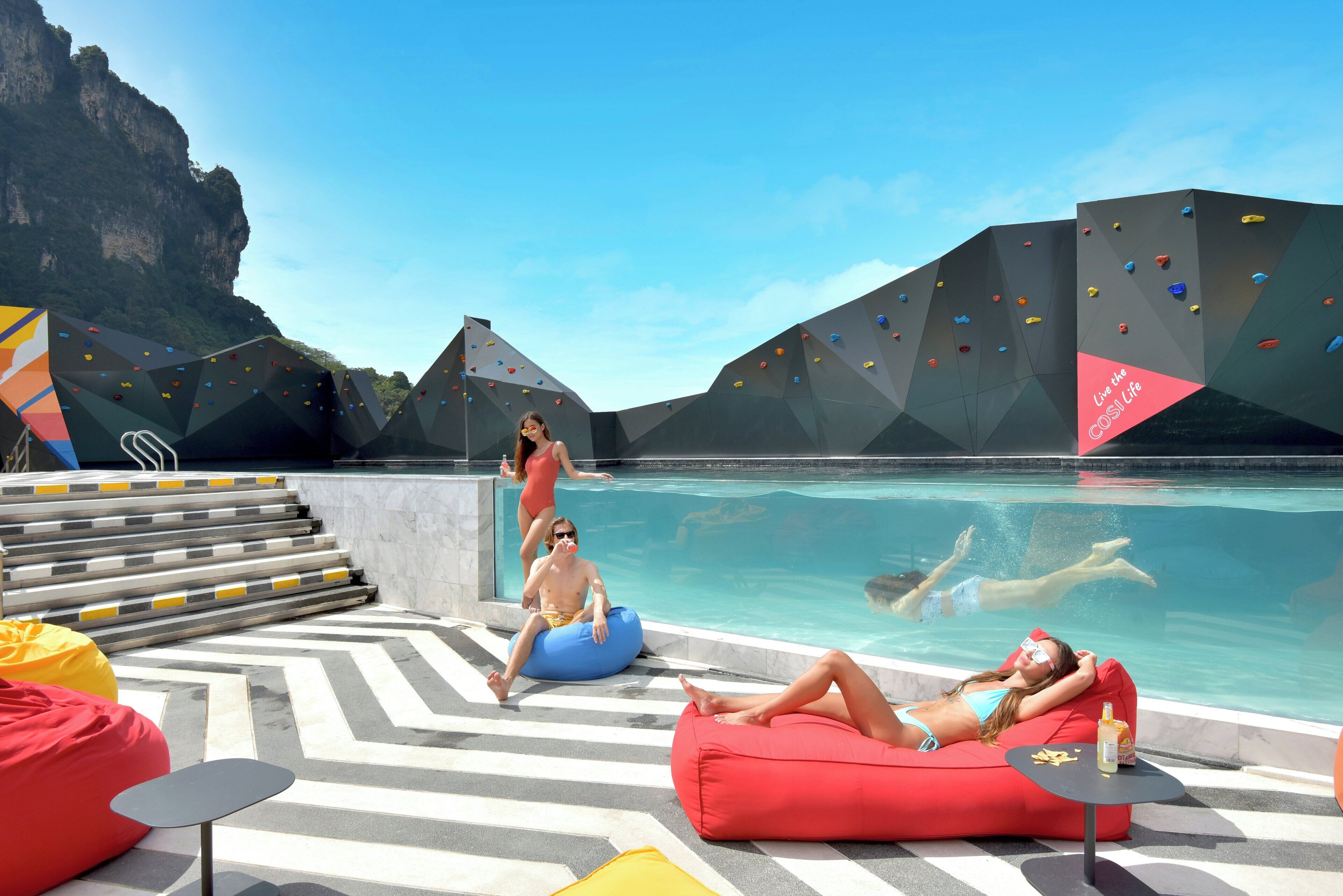 A pool area with climbing walls, a pool, and a view of a mountain.