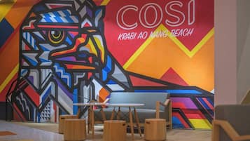 A modern interior with a colorful mural, a sofa, and wooden stools.