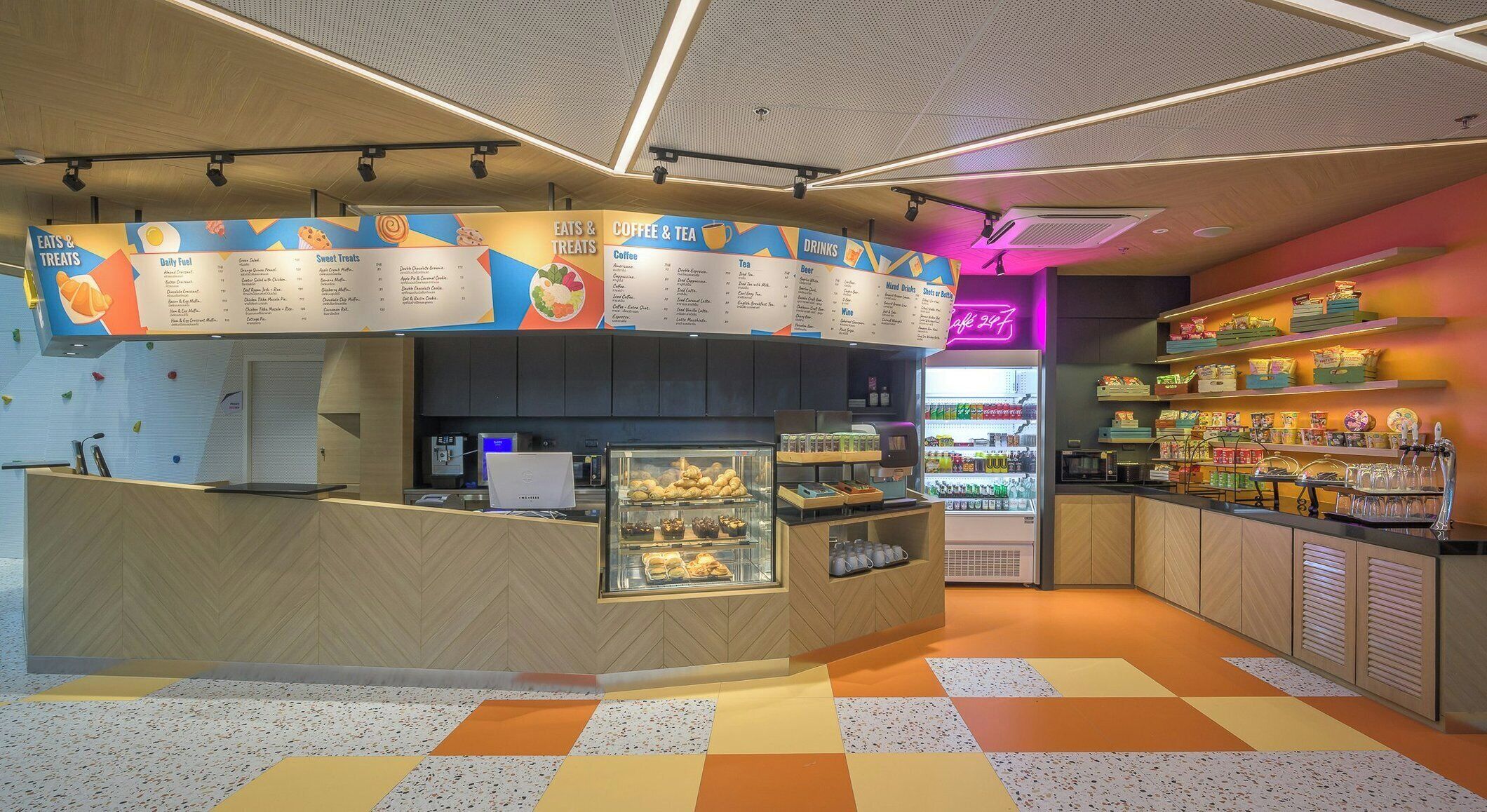 A café with a menu board, a coffee machine, and a display of drinks.